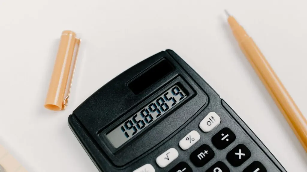 Calculadora, moedas e material de escritório sobre mesa branca