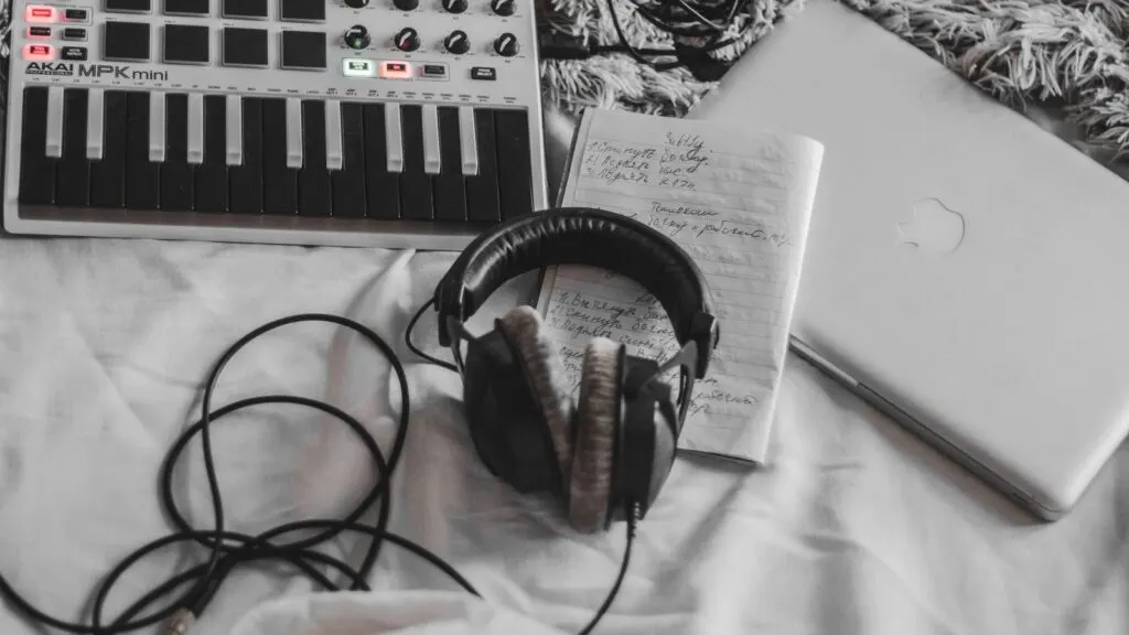 Controlador MIDI, fones e notebook num setup caseiro de produção musical