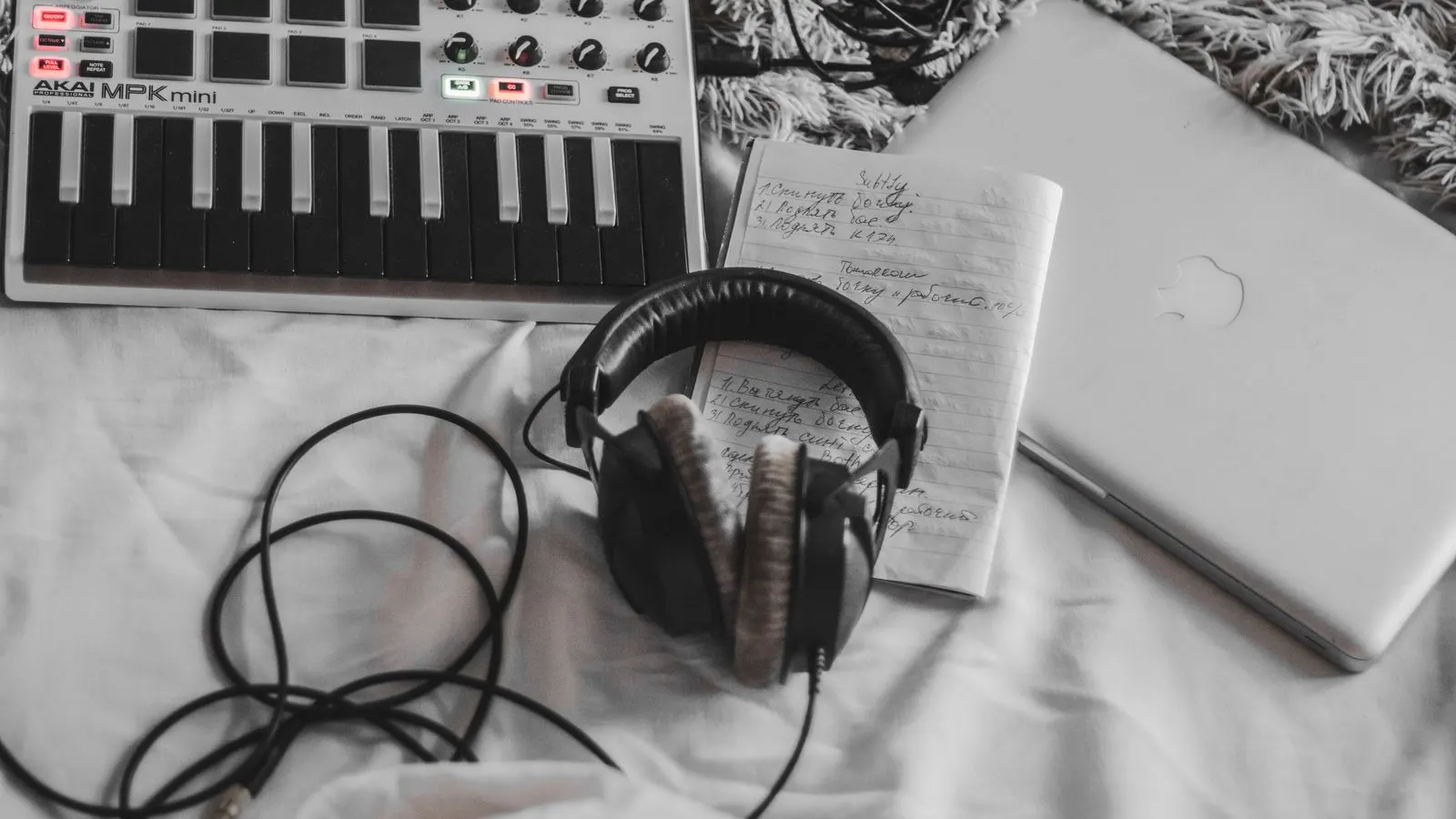 Controlador MIDI, fones e notebook num setup caseiro de produção musical